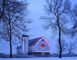 Iowa farmstead with a barn decorated in Christmas lights at dusk during winter