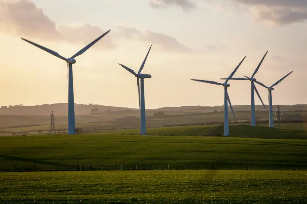 Wind turbines on farmland producing renewable energy across rolling fields at sunset