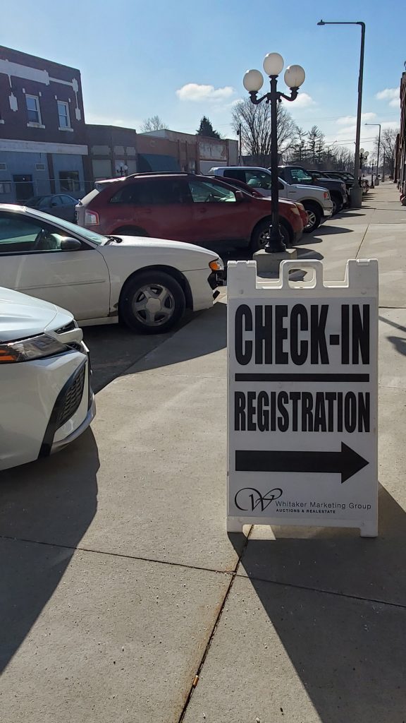 Auction check-in and registration sign directing bidders at a live auction event