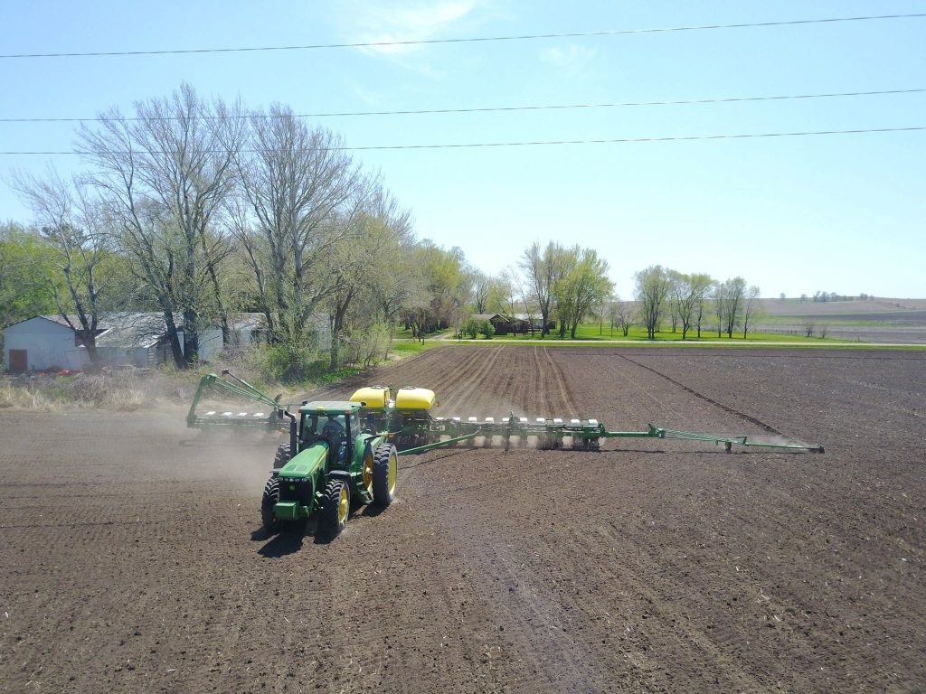 Tractor planting crops on Iowa farmland showing active agricultural production