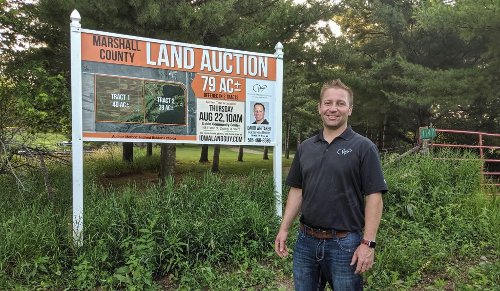 David Whitaker standing beside a Whitaker Marketing Group land auction sign for a 79-acre Marshall County farmland sale.