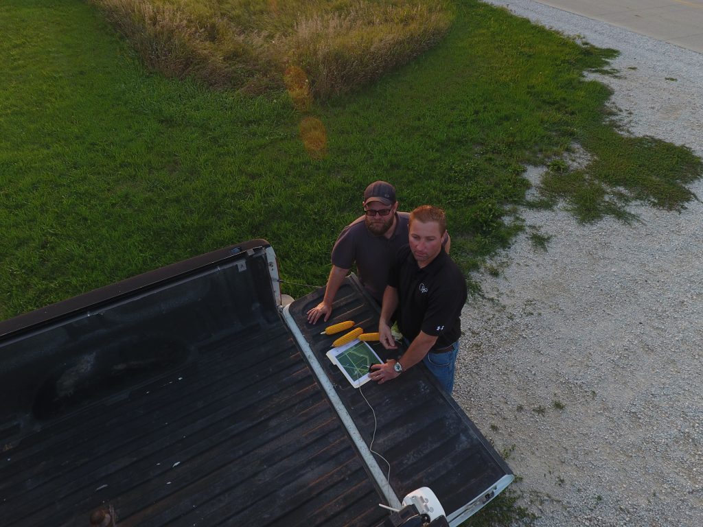 Two land professionals reviewing property maps in the back of a pickup truck while inspecting Iowa land.