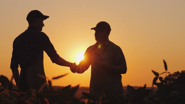 Farmland owner shaking hands with a trusted farmland broker at sunset