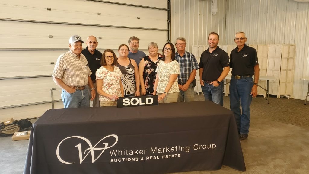 Whitaker Marketing Group team and sellers standing behind a SOLD table sign after a successful auction closing.