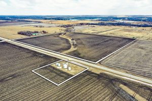 Drone aerial of Webster County Iowa farmland with white boundary lines showing two tracts and grain bin site.
