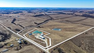Aerial view of Ringgold County, IA land for sale—Tract 1 (107.70± acres) with the boundary outlined in white, showing a building site, pond, and surrounding cropland.