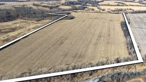 Aerial view of Ringgold County, IA farmland for sale—Tract 8 (98.7± acres) with the boundary outlined in white, showing a large open field bordered by timber and a creek corridor—ideal hunting habitat.