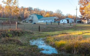 Bunker MO land for sale with creek water access, farmhouse-style home, barn, and shop at Spring Haven Homestead