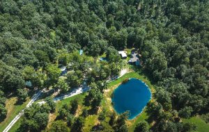 Aerial view of Dent County Missouri cabin rental property for sale with fishing pond, cabins, and wooded Ozarks acreage near the Current River