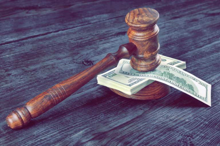 Auction gavel on cash representing buyer’s premium and auction fees in farmland sale