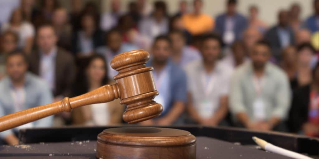 Farmland auction with bidding competition shown by auctioneer gavel and crowd of bidders