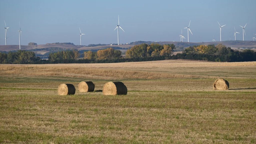 Farmland with hay bales and wind turbines representing land sales and auctions