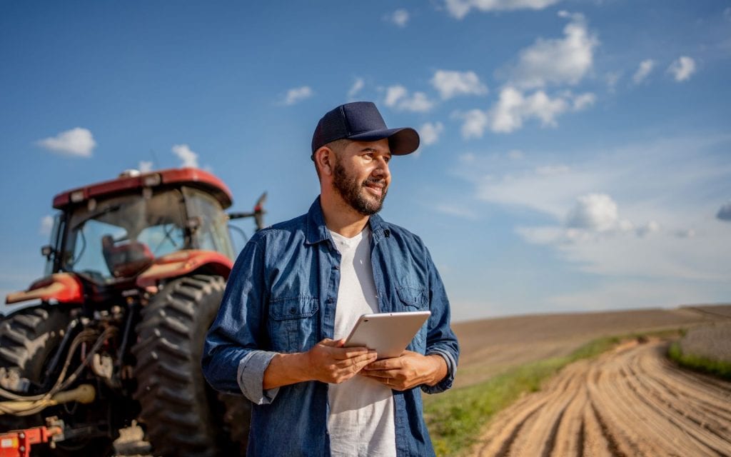 Successful landowner using tablet technology to manage farmland and make informed decisions about land stewardship, sustainability, and property value.