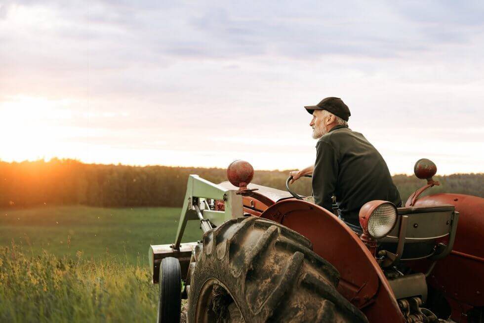 Farmer operating a tractor on productive farmland while managing a leased farm