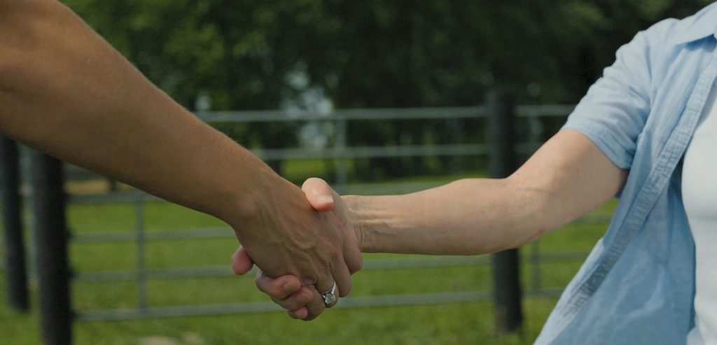 Trusted land professionals shaking hands with a landowner after a successful farmland consultation in Iowa.